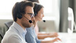 © fizkes - Confident call center operator agent in headset with microphone consulting client online close up, busy employee working in customer support service office, coworking space, horizontal photo