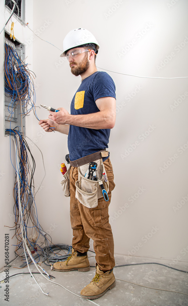 Electrician Builder at work, examines the cable connection in the ...