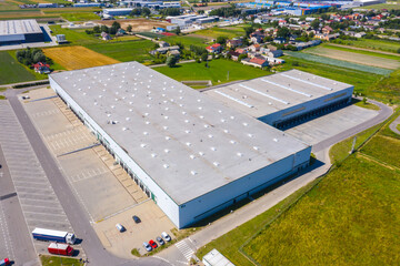 Wall Mural - Aerial view of goods warehouse. Logistics center in industrial city zone from above. Aerial view of trucks loading at logistic center. View from drone.