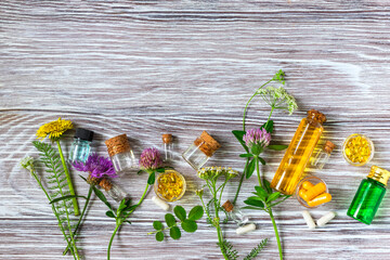 Wall Mural - Medical flowers herbs essential oils in bottles for natural diseases treatment on wooden table. Concept of natural cosmetics.