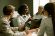© Svyatoslav Lypynskyy - Happy business people chat at business meeting in office. Selective focus on African woman sharing ideas with colleagues. Tinted image.