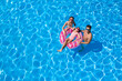 Happy family with inflatable ring in swimming pool, space for text. Summer vacation