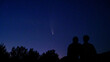 © YOUproduction - Silhouette of couple, man and woman looking at Comet NEOWISE in the night sky at sunset. Comet under the starry sky, in the evening, between the stars. Romantic family date near river and space.