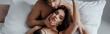 Horizontal crop of handsome man touching face of beautiful girl in bra on bed on grey background