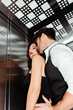 © LIGHTFIELD STUDIOS - Low angle view of man embracing seductive woman with red lips in elevator