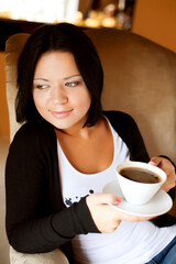 Wall Mural - young woman sitting in a cafe drinking coffee