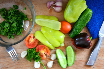 Vegetables in close-up on the cutting Board. Ripe tomatoes, cucumbers, bell peppers, parsley, garlic are prepared for a vitamin salad. The view from the top.