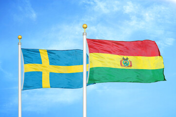 Sweden and Bolivia two flags on flagpoles and blue sky