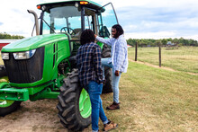 Brothers Chatting Next To Tractor On Farm