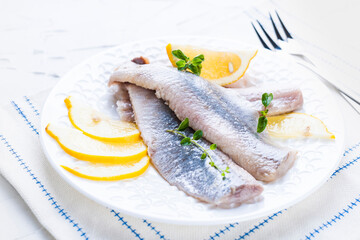 Dutch herring. Traditional Dutch food, marinated fish fillet with onion and lemon. Food high in nutrients and vitamins. Photo in light colors, free space for text. 