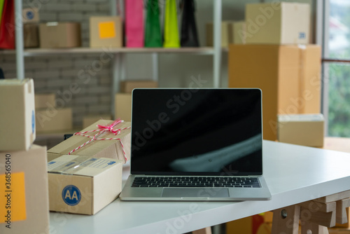 Laptop computer with empty screen on shipping box background. Concept of online retail store, delivery order and customer service.
