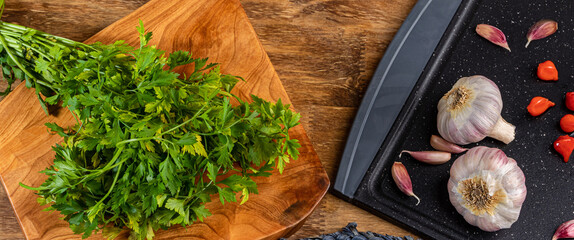 Cutting board with garlic, beak pepper and parsley on wood.