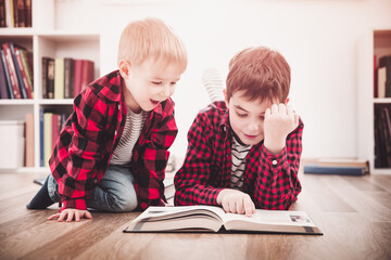 Wall Mural - Three years old child and his older brother sitting among books at home