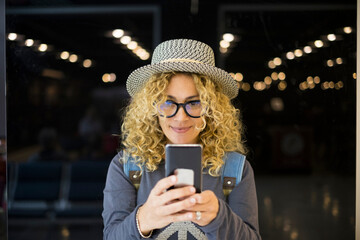 portrait and close up of beautiful curly and blonde woman looking at the camera smiling - happy people traveling at the airport - vacations outdoors