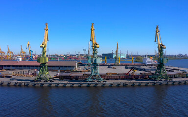 Aerial view of a row of construction or cargo cranes on the river bank.