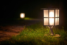Illuminated Garden Alley In The Night. Lantern On Hook Illuminating The Board Of The Yard