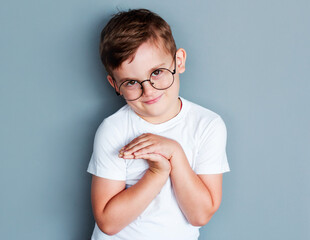 Wall Mural - The little boy wearing a white t-shirt on gray background in studio