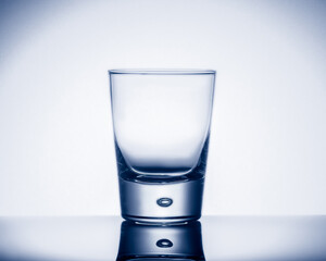 Empty glass on reflective surface on white background