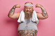 © wayhome.studio  - Motivated overweight bearded man raises arms, shows muscles after training, wants to be strong and have biceps, leads healthy lifestyle, has fitness program for weigt loss, faith in himself.