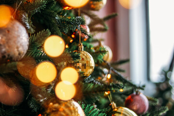 Wall Mural - Decorated Christmas tree in gold and purple toys with lights bokeh textured background