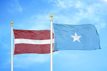 Latvia and Somalia two flags on flagpoles and blue sky