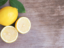Half And Group Of Fresh Lemon With Leaves On Wooden Background With Copy Space. High Vitamin C, Which Helps Control Weight And Reduce Cancer Risk. ..