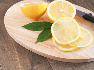 Slice lemon fruit with leaves and knife on cutting board. Close up, Copy space for text. High Vitamin C..