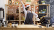 © PRPicturesProduction - woman coffeehouse staff against red bricks wall listening to music and dancing in counter bar. girl barista in santa hat having fun and moving in cafe store. waitress enjoy christmas party in shop