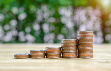 Money coin stack growing graph on wood table in the public park background.saving money and investment concept.