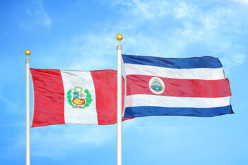 Peru and Costa Rica two flags on flagpoles and blue sky