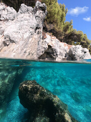 Underwater split line photo of beautiful caves with deep turquoise sea and Pine trees of Kastani beach well known for Mamma Mia movie filming, Skopelos island, Sporades, Greece