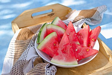 Wall Mural - Sliced juicy watermelon on a white plate on a wooden tray. Summer concept. Summer snacks.