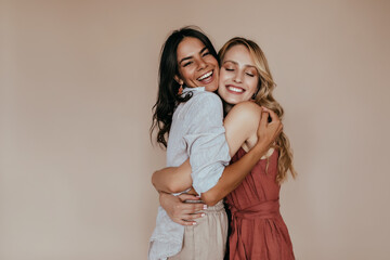 pretty girls with trendy makeup embracing on light background. excited caucasian sisters expressing 