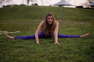 Yoga model stretching her body during a workout session at the park. Shot with natural light at sunset.