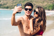 © Art_Photo - Romantic lovers young couple relaxing together on the tropical beach.Man and woman taking selfie with smartphone and enjoy life.Summer vacations