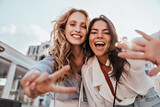 Fototapeta  - Lovable caucasian girls expressing positive emotions to camera. Outdoor photo of refined sisters posing on sky background.