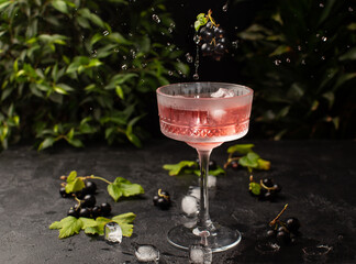 Wall Mural - Fresh berries cocktail with black currant and ice in crystal glass.Studio shot of drink in freeze motion,flying drops and berries.Summer cold drink.