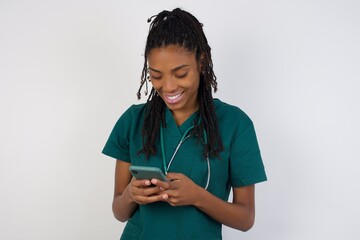 Blonde smiling young woman demonstrating white teeth using cell phone, messaging, being happy to text with her boyfriend, looking at screen of smartphone. Modern technologies and communication