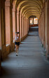 Teen in shorts, sports bra and sneakers with headband running through portico