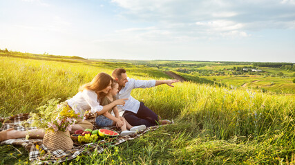 Wall Mural - Beautiful family together on a picnic outdoors in meadow