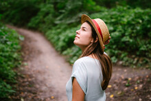 Young Woman In Straw Hat In A Summer Forest. Pretty Young Lady Walking In The Wood. A Beautiful White Lady In Vintage Brimmed Hat. A Student Walks In Nature On A Day Off. Girl Goes Hiking After Class