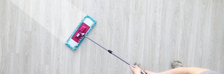 Male hant hold plastic mop and wash dirty ploor closeup background. Professional cleaning concept