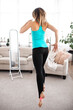 © Admiral - Back view of a sport woman who is exercising fitness looking at the mirror at home. Workout in living room