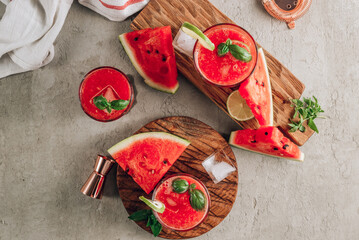 Wall Mural - Watermelon lemonade with lime and fresh basil leaves on concrete background. Refreshing summer drink