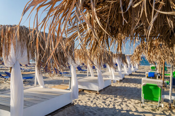 Straw beach umbrellas and sun chairs on the east coast of Zakynthos island in Greece