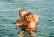 © amelie - Grandfather and toddler girl with swimmies in sea