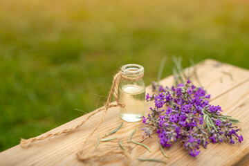 Herbal oil and lavender flowers on wooden background