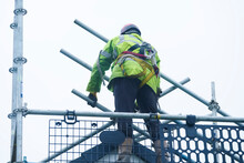 Scaffold Worker Dismantling Access Structure On Construction Building Site