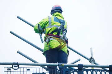 Wall Mural - Scaffold worker dismantling access structure on construction building site