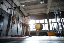 Fit Man Throwing Medicine Ball Doing Ball Slam Against Gym Floor Or Shoulder Press Upper Body Workout Exercise. Cross Training At Fitness Center.